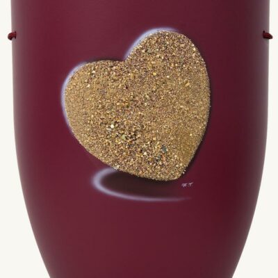 Weinrote Biourne die mit einem Reliefherz aus echtem Sand geschmückt ist.